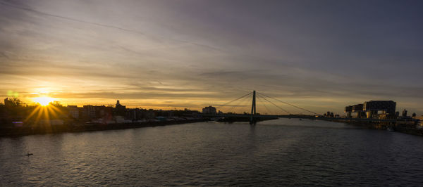 View of bridge over river against buildings during sunset