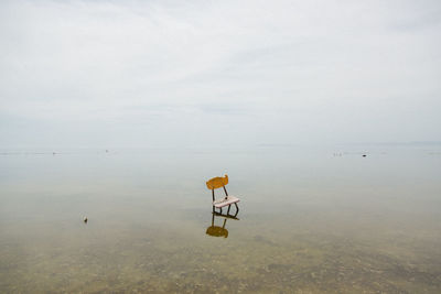 Abandoned chair at sea against sky