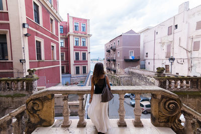 Rear view of woman in city against sky