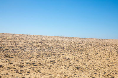 Scenic view of desert against clear blue sky