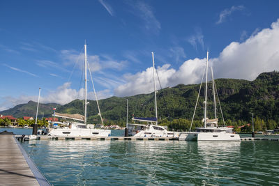 Sailboats moored at harbor in eden island, seychelles against sky