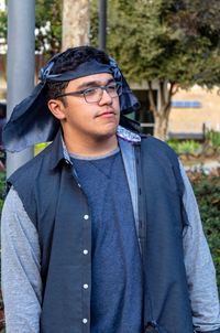 Handsome young man looking away while standing in park