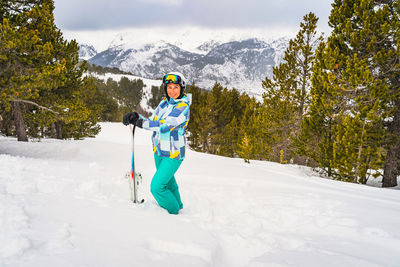 Portrait of a woman standing in deep snow and holding ski, andorra, pyrenees