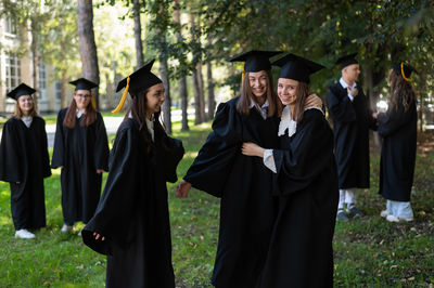 Portrait of woman wearing graduation gown standing in forest