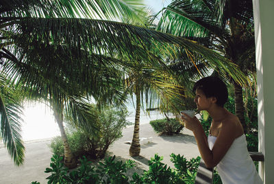 Side view of woman standing by palm trees