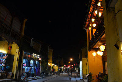 Low angle view of illuminated street amidst buildings at night