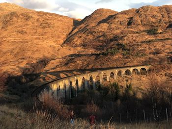 Arch bridge over river against mountain