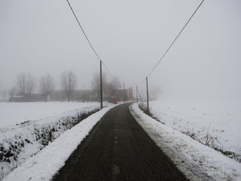 Road amidst snow covered landscape against sky