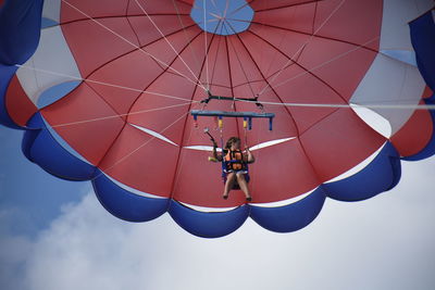 Low angle view of men hanging against sky