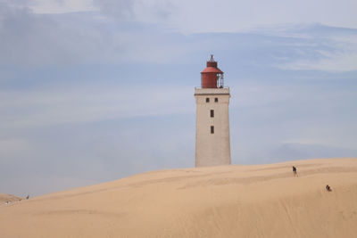 Lighthouse on beach against sky