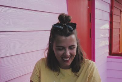 Close-up of smiling young woman against wall