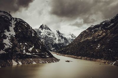 Scenic view of snow covered mountains against cloudy sky