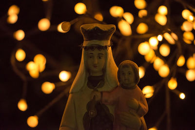 Statue of virgin mary and christ against illuminated lights