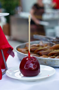 Apple in red caramel on wooden stick