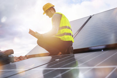 Low angle view of man with arms raised standing against sky
