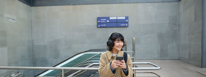 Portrait of young woman standing against wall