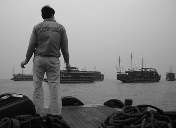 Rear view of man standing at harbor