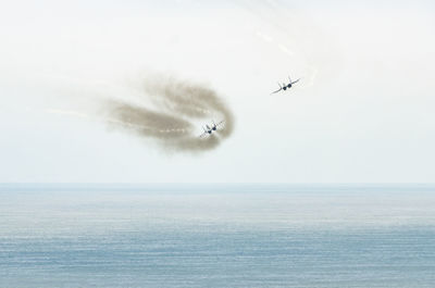 Airplane flying over sea against sky