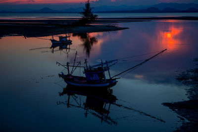 Sailboats moored in lake against sky at sunset