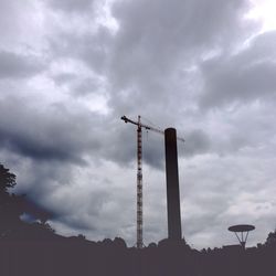 Low angle view of crane against cloudy sky