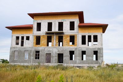 Low angle view of old house on field against sky