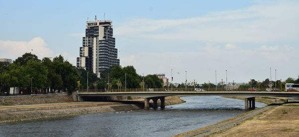 Bridge over river in city against sky