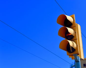 Low angle view of traffic signal against clear blue sky