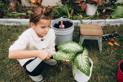 A girl spraying water on plant's leaves