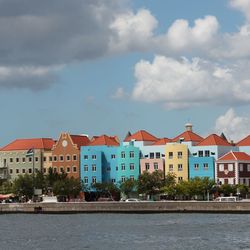 Buildings by river against sky