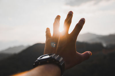 Cropped image of person gesturing against sky during sunset