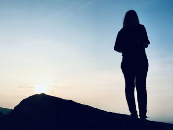 Rear view of silhouette woman standing on mountain against sky