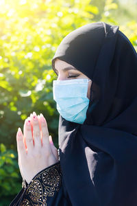 A woman from east in national islamic clothes holds religious supplies in her hands.