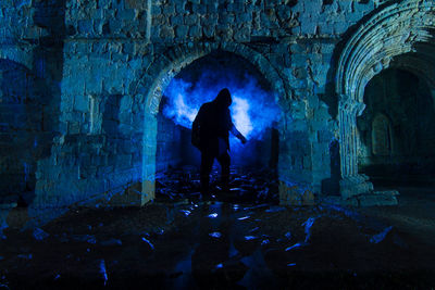 Rear view of man amidst abbey ruins at night