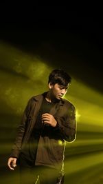 Young man standing against black background