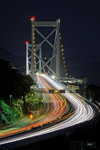 Light trails on bridge against sky at night