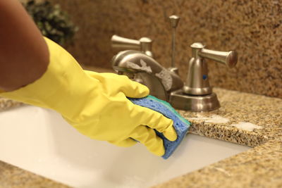 Cropped hands of woman washing sponge in bathroom