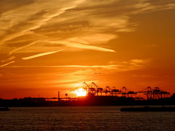 Silhouette commercial dock against sky during sunset