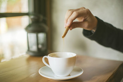 Hand holding coffee cup on table
