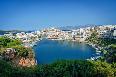 High angle view of townscape by sea against clear blue sky