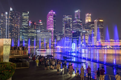 People at spectra show of dancing fountains, light show along promenade by marina bay sands