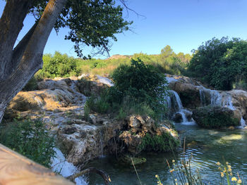 Scenic view of waterfall in forest against sky