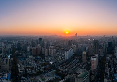 Aerial view of buildings in city against sky during sunset