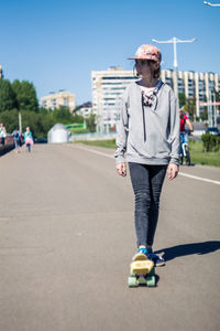 Girl skateboarding on road against sky