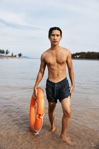 Portrait of shirtless man exercising at beach