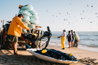 Men fishing on beach against sky