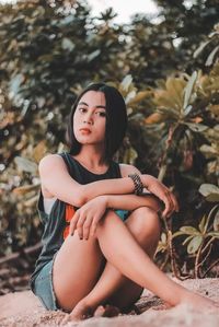 Young woman looking away while sitting on land