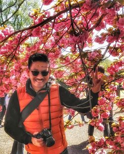 Portrait of young man standing by flower tree