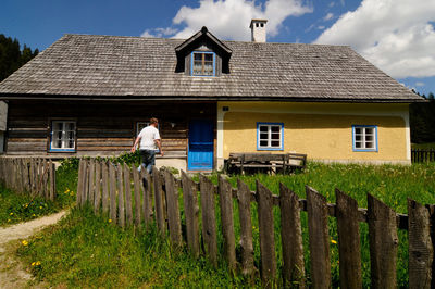 Full length of man outside house on field against sky