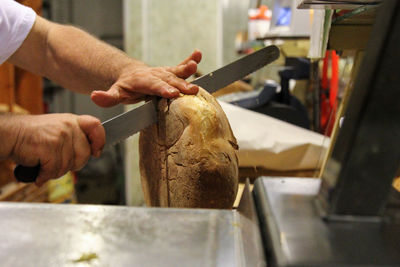 Close-up of hands cutting bread