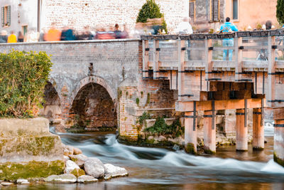 Arch bridge over river against buildings